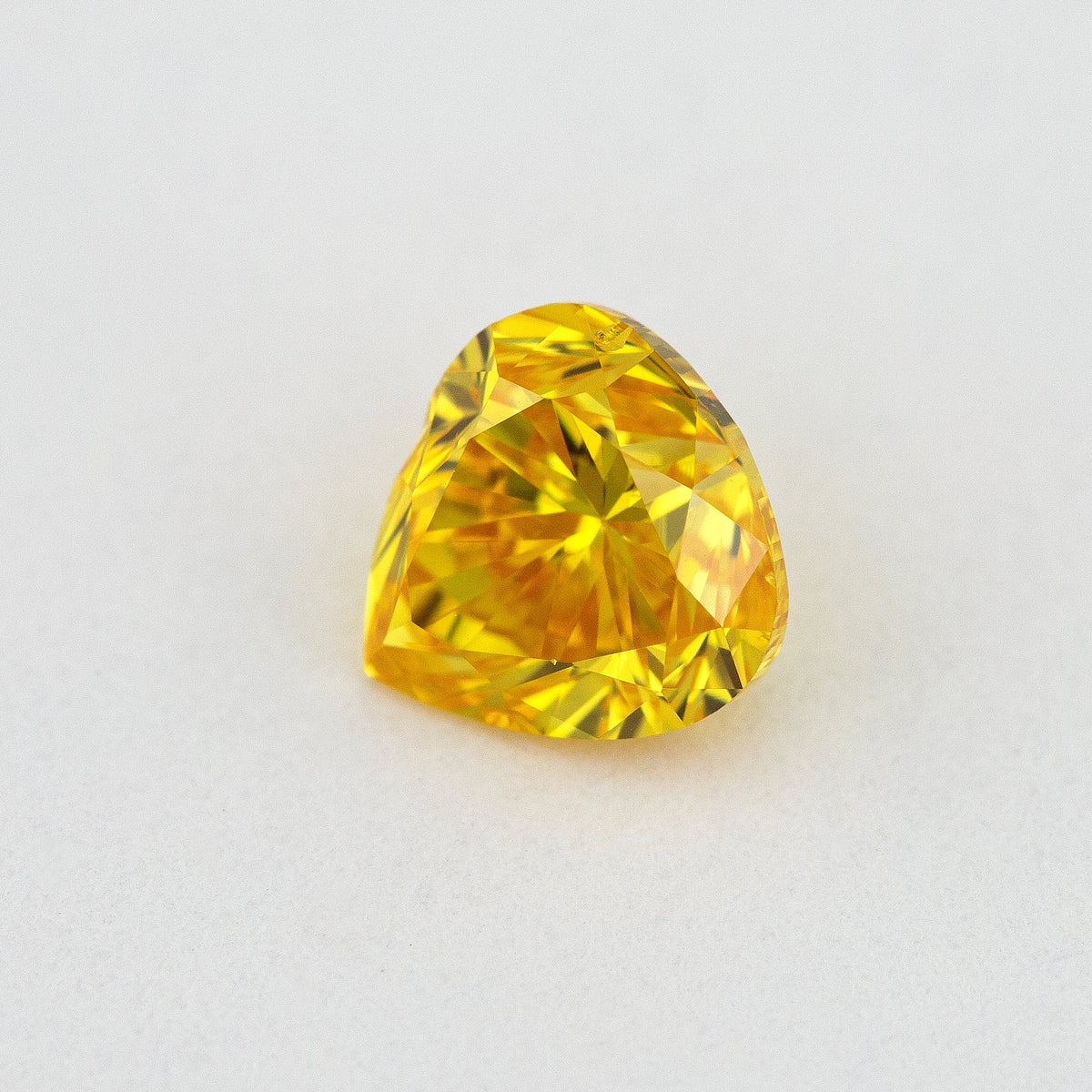 Different face-up angle of the yellow-orange heart-shaped diamond showing its table and crown facet reflections.