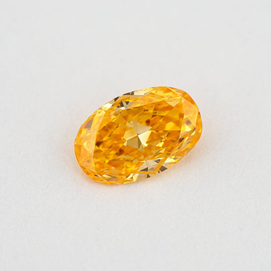 Face-up oval orange diamond on a pale surface, showing its elongated outline, central table and yellow flashes.