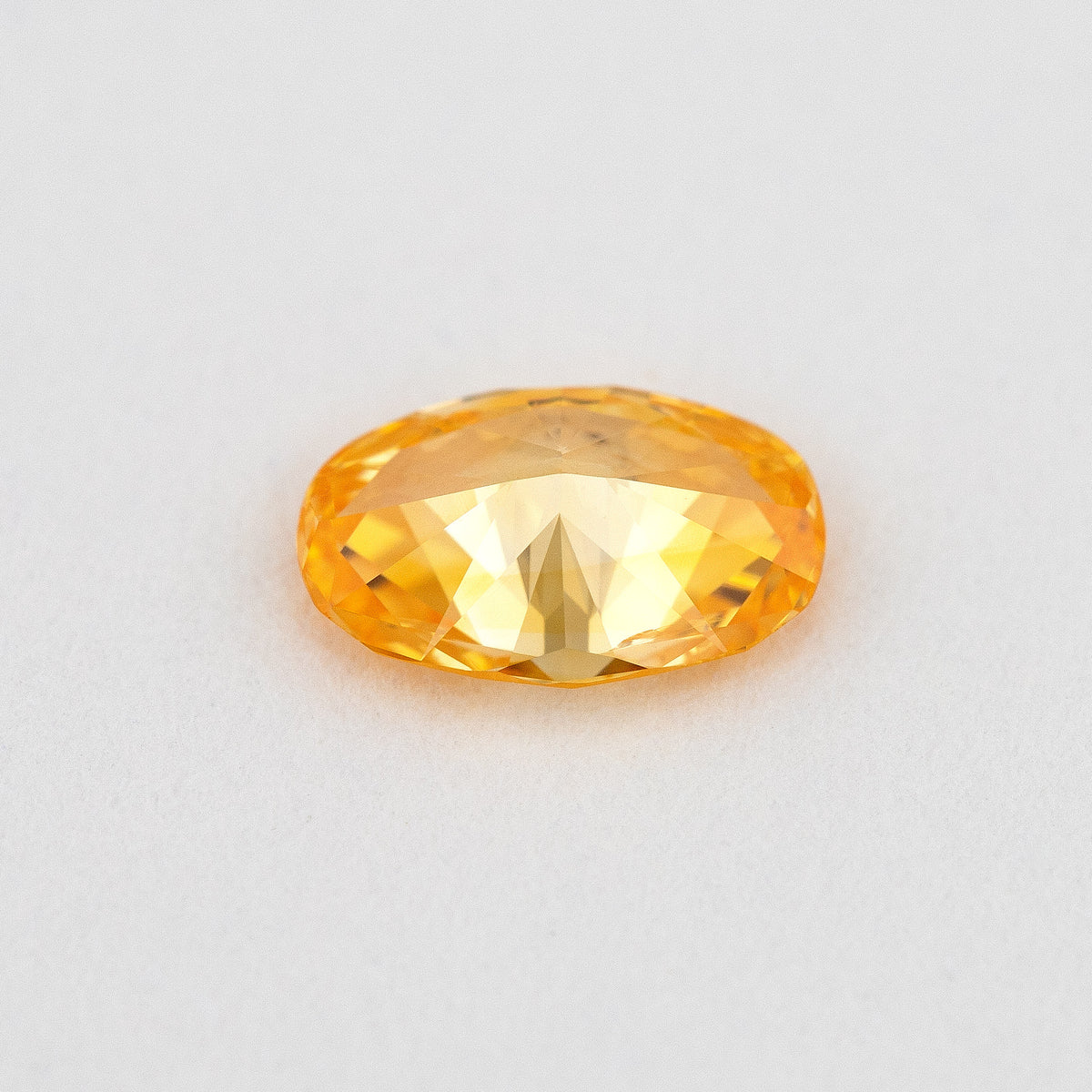 Pavilion and back view of the oval orange diamond, showing its rear facets and elongated outline.