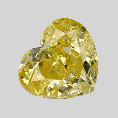 Yellow heart-shaped diamond leaning diagonally on a pale background, with alternating light and dark reflections.