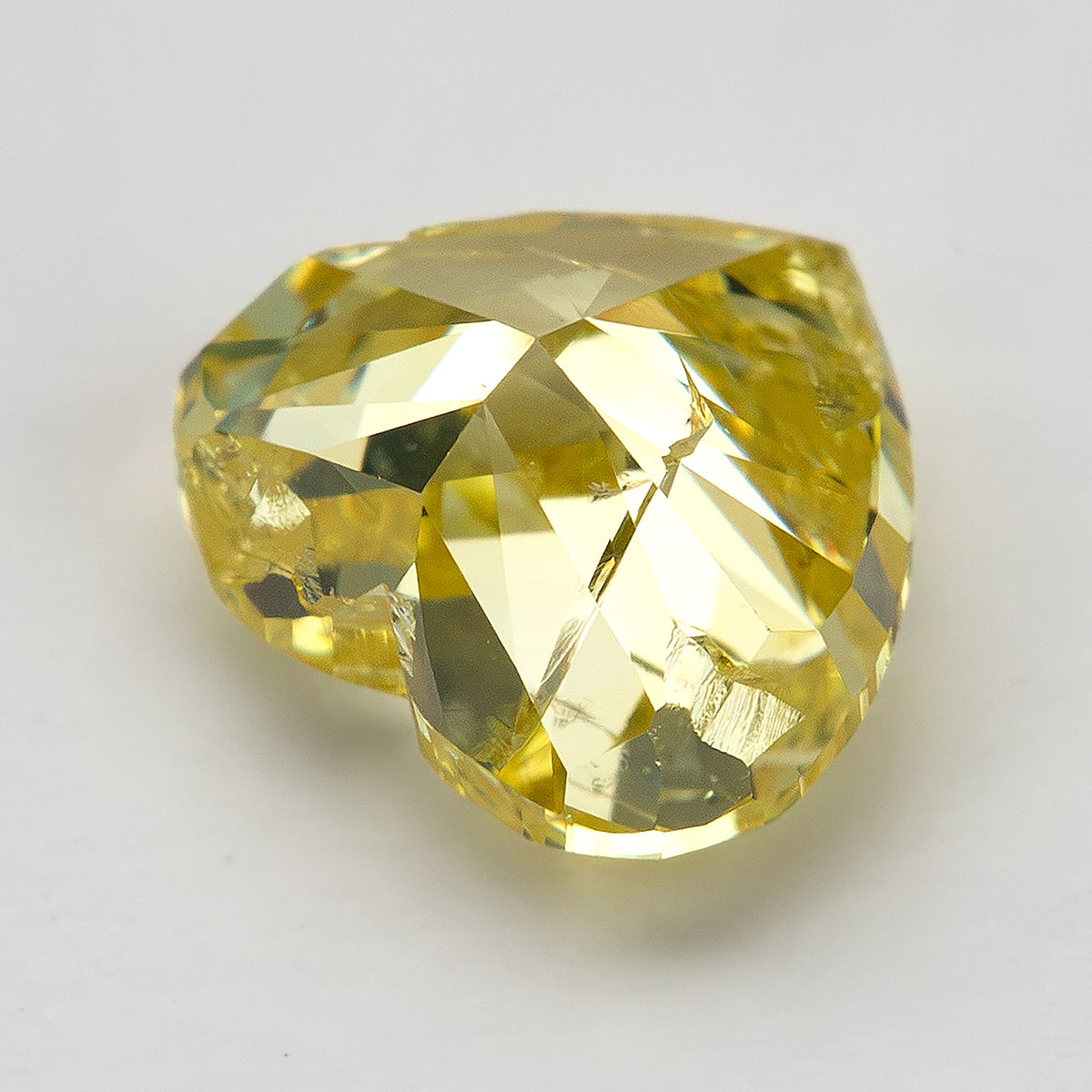 Yellow heart-shaped diamond tilted sideways to show its pavilion and broad triangular reflections.
