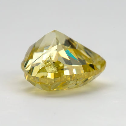 Low side profile of the yellow diamond on a pale surface, showing the raised crown and tapering pavilion.