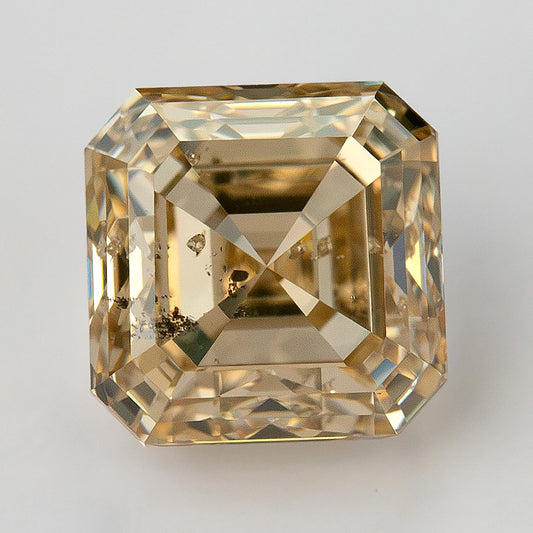 Face-up champagne-colored Asscher-cut natural diamond on a light background, showing stepped facets and dark clarity characteristics.