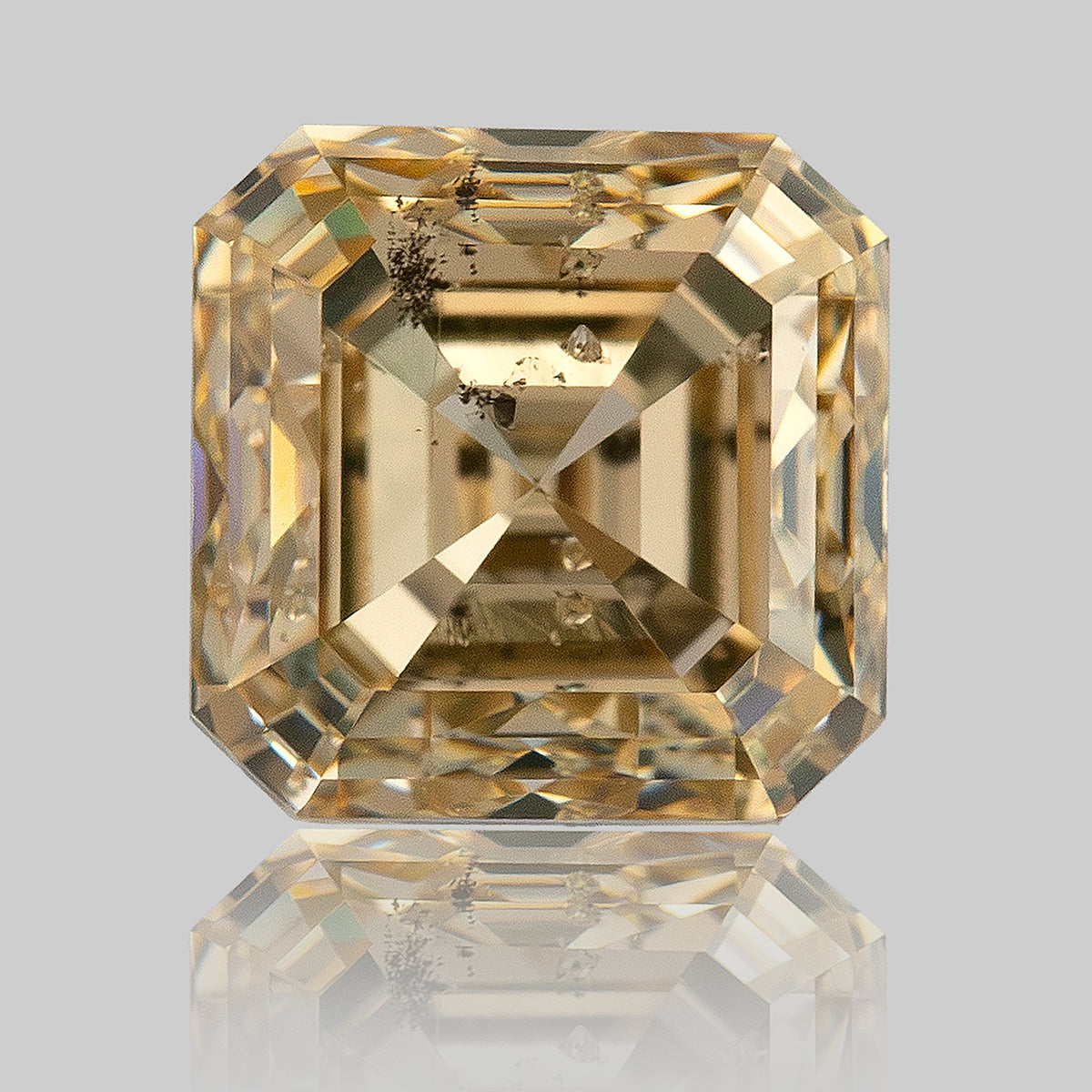 Upright face-up Asscher-cut diamond above its reflection, showing warm step-facet bands and dark inclusions.