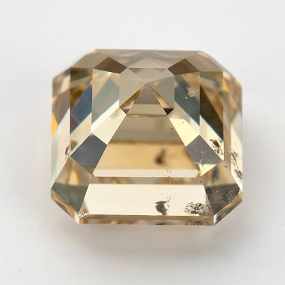 Oblique crown view of the champagne diamond with broad reflective facets and dark clarity characteristics near its edge.