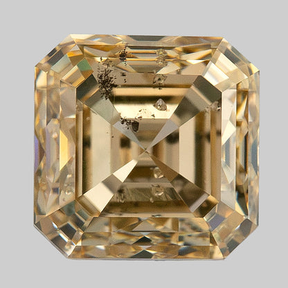 Warm face-up macro of the square diamond showing strong stepped reflections and clustered dark characteristics.
