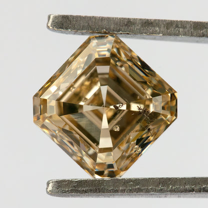 Pavilion-facing champagne diamond in tweezers, oriented diagonally with intersecting reverse facets visible.