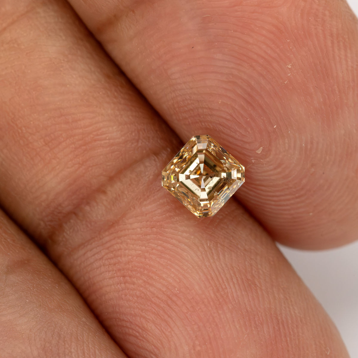 Champagne Asscher-cut diamond resting diagonally on the hand, with fingertips showing its size.