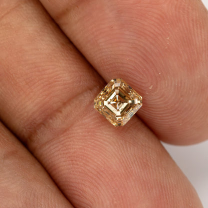 Champagne Asscher-cut diamond resting diagonally on the hand, with fingertips showing its size.
