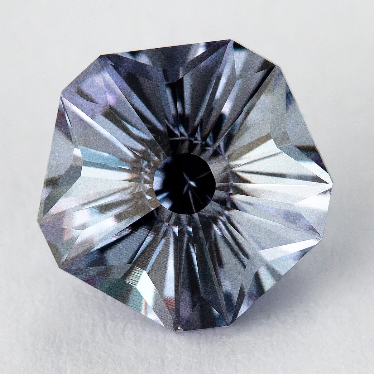 Pentagon Hanami-cut lab-grown sapphire with a dark central reflection and alternating bright and dark blue-gray facets.