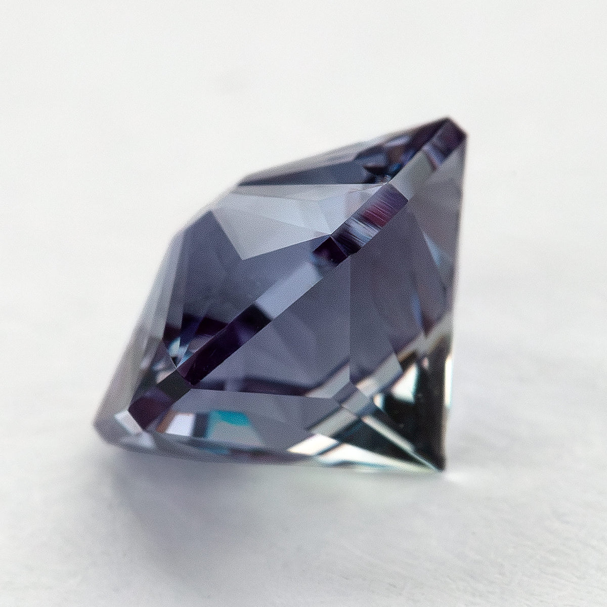 Low side angle of the lab-grown pentagon sapphire showing the crown and depth above a light surface.