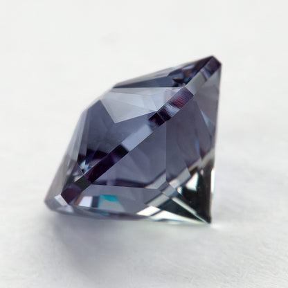 Low side angle of the lab-grown pentagon sapphire showing the crown and depth above a light surface.
