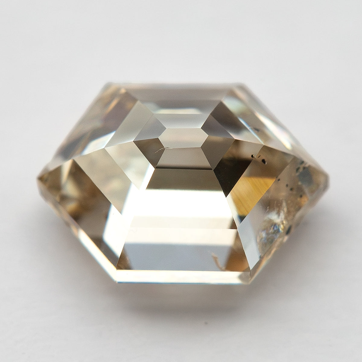 Side view of the natural champagne step-cut diamond in tweezers