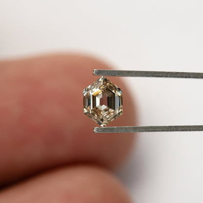 Champagne hexagon diamond held in tweezers, showing its geometric outline