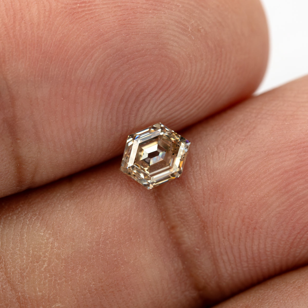 Loose champagne hexagon diamond shown on hand for scale