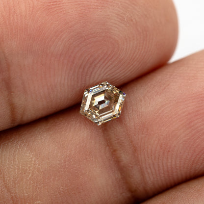 Loose champagne hexagon diamond shown on hand for scale