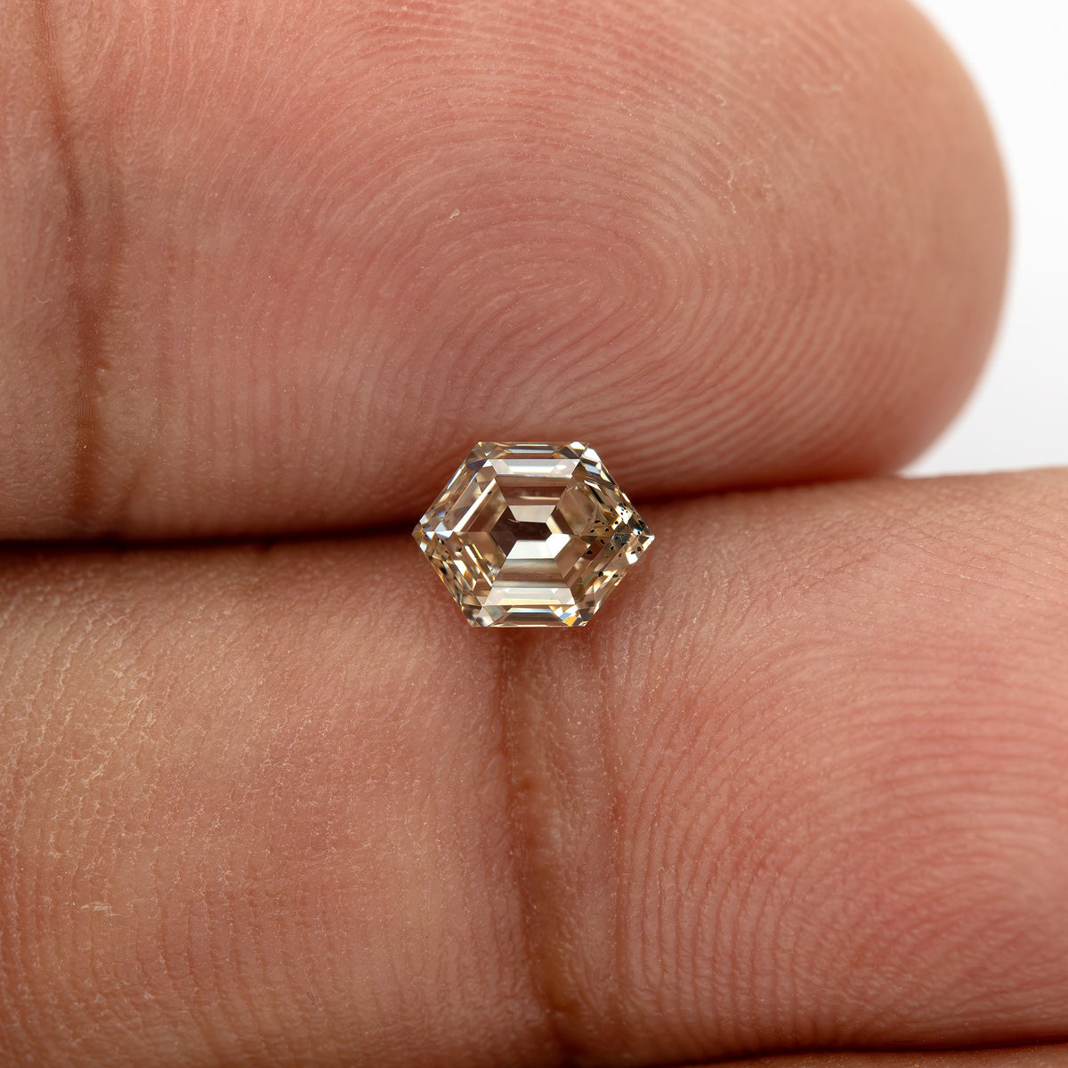 Hand-scale close-up showing the diamond's warm brownish yellow appearance