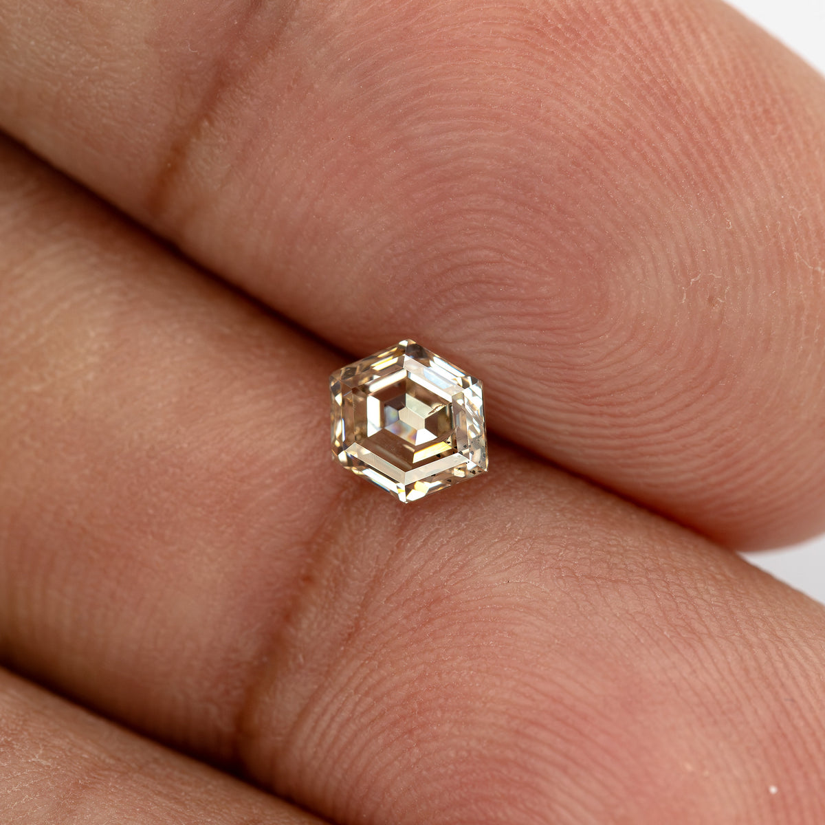 Old Mine-style hexagon diamond shown on a finger for size reference
