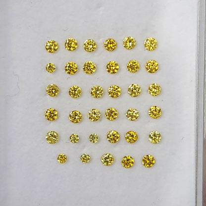 Face-up yellow round diamonds arranged in rows on a white display pad.