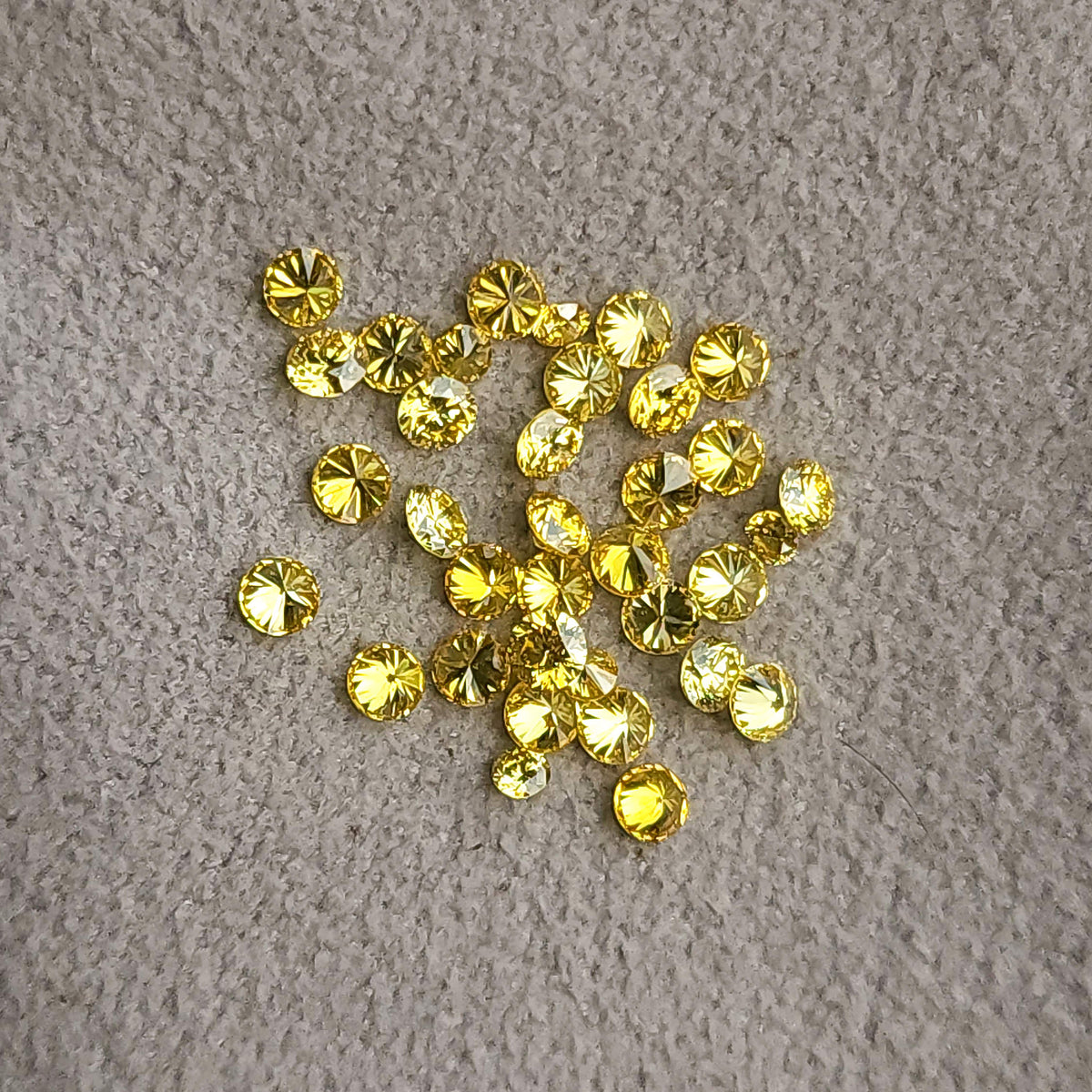 Loose yellow diamonds scattered on a textured grey surface.