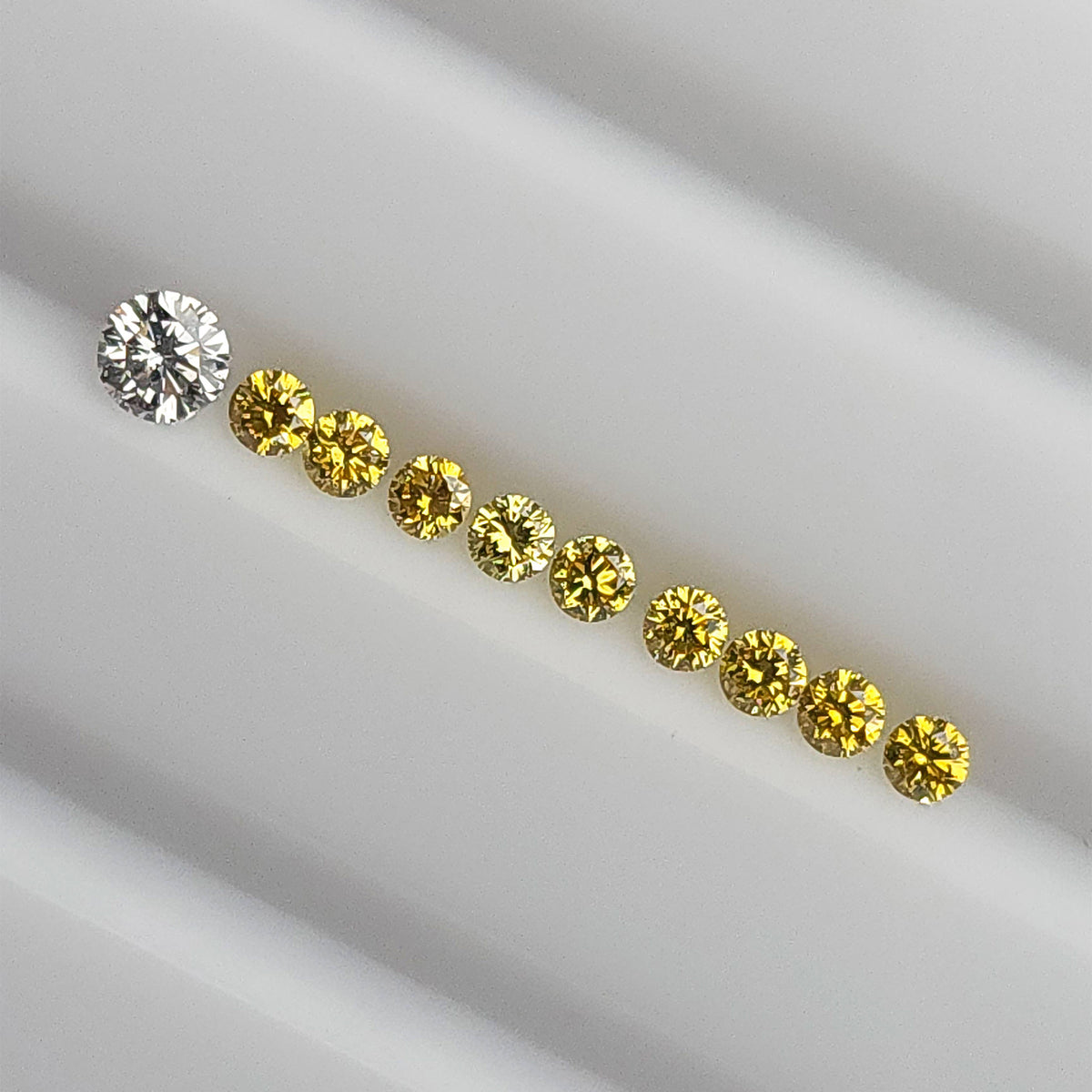 Yellow diamonds in a diagonal face-up line beside an excluded white comparison diamond.
