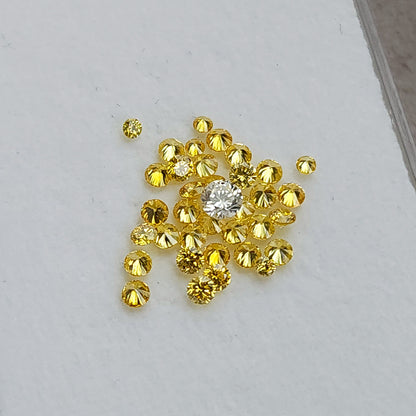 Loose yellow diamond cluster on a pale surface with an excluded white comparison diamond.
