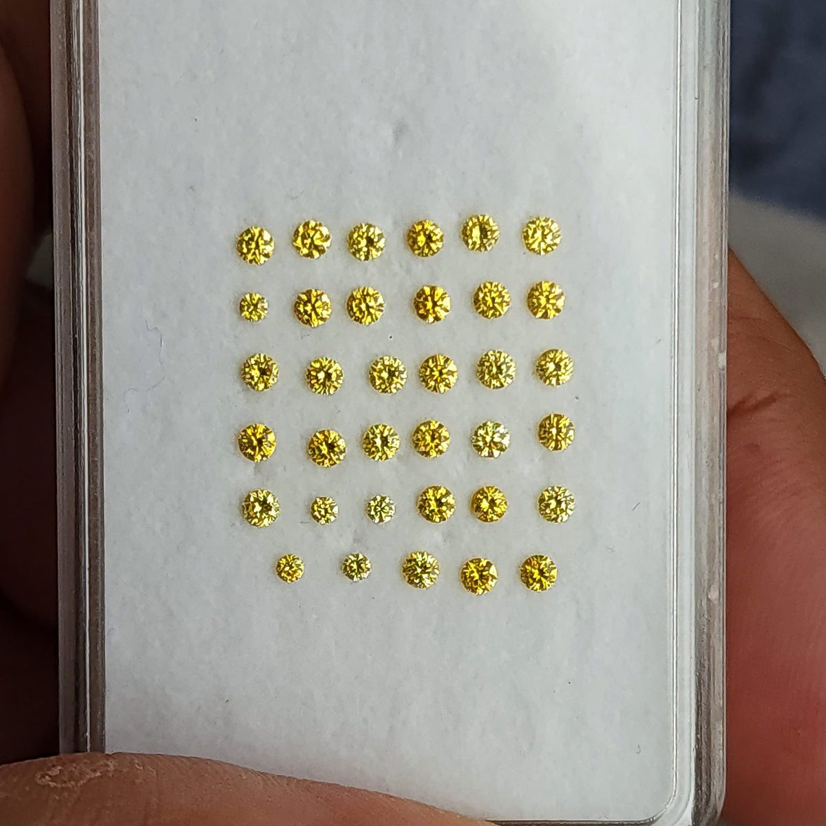 Front view of yellow diamond rows in a narrow display held by fingers.