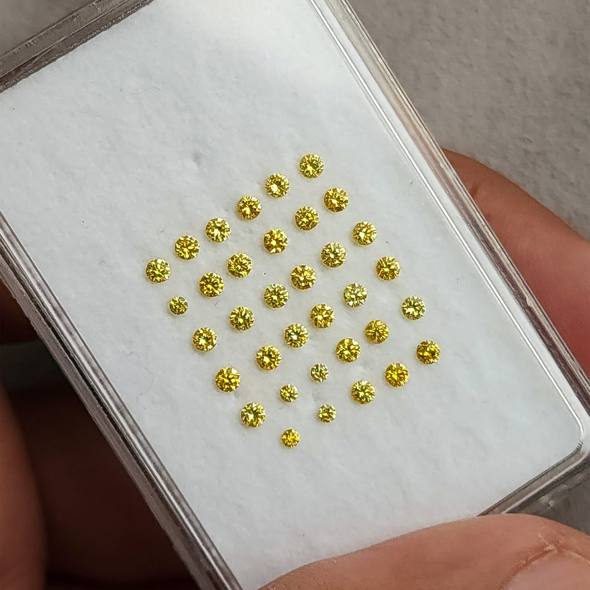 White display pad of yellow diamonds tilted in a hand.