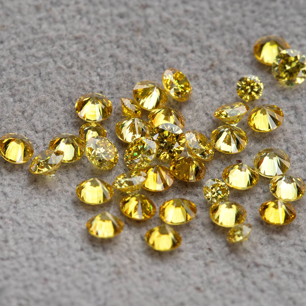 Yellow diamonds viewed at a low angle on grey; a white comparison diamond is not included.