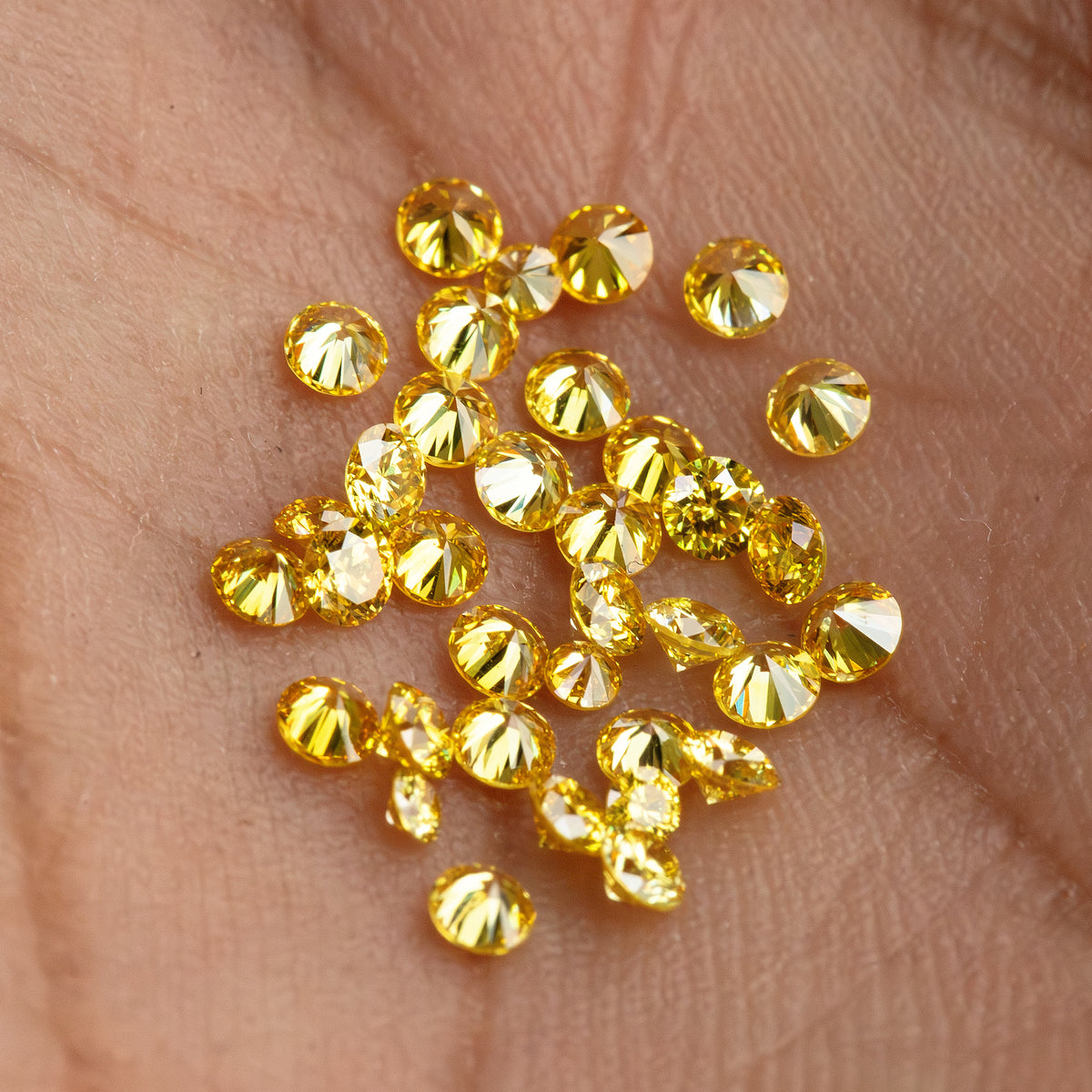 Close palm-scale view of yellow diamonds with an excluded white comparison diamond.