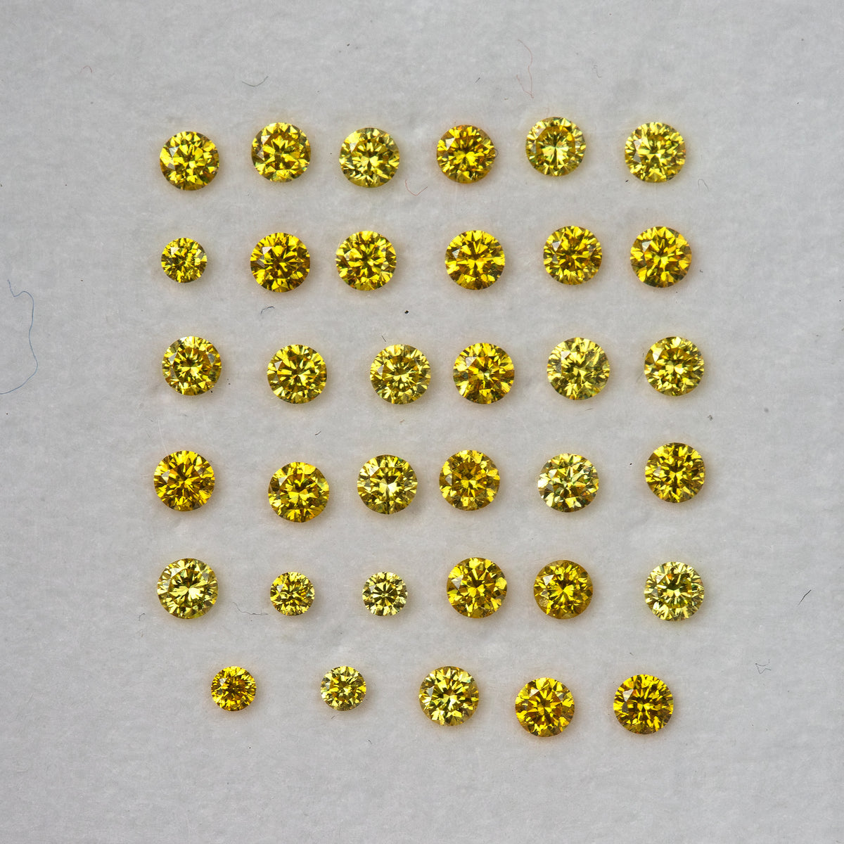 Face-up yellow diamond rows on a white background, showing a range of yellow reflections.