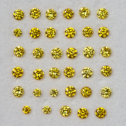 Closer face-up display of yellow diamonds in even rows on a pale background.