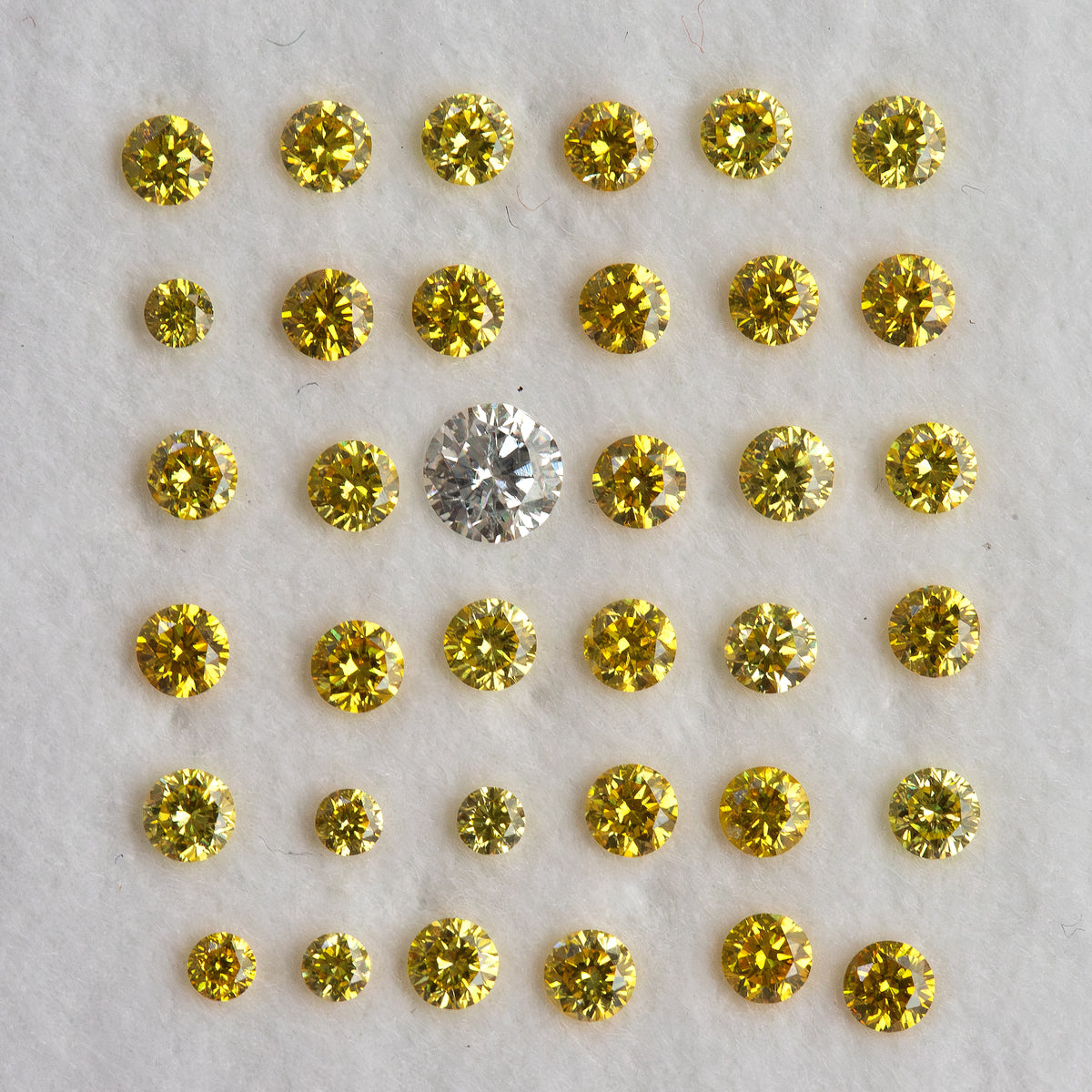 Yellow diamond rows around an excluded white comparison diamond on a pale pad.