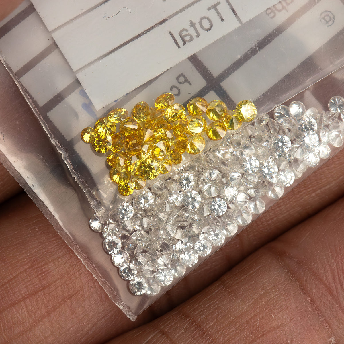 Container with grouped yellow and white diamonds held in a hand; white diamonds are comparison only and excluded.