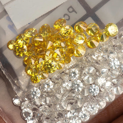 Close hand-held container view of yellow diamonds alongside excluded white comparison diamonds.