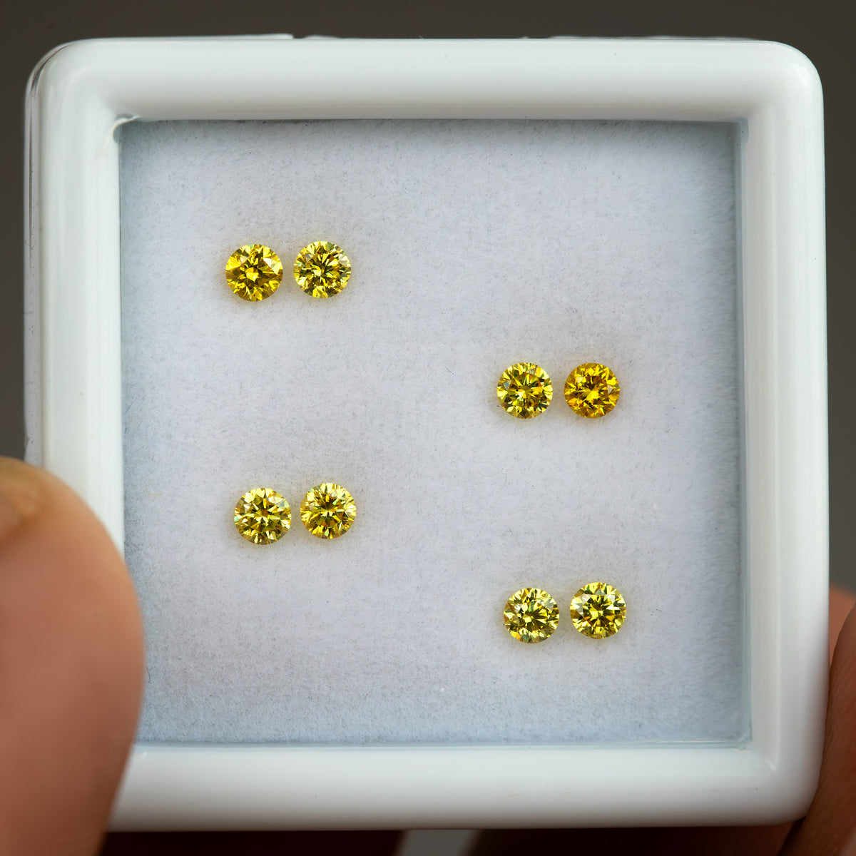 Close front view of four yellow diamond pairs in a white tray.