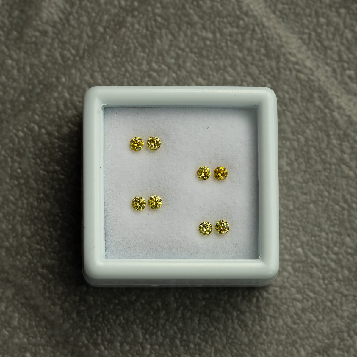 Wider view of the four-pair white tray on a textured grey surface.