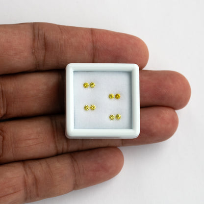 Four yellow diamond pairs in a small white tray on a palm for scale.