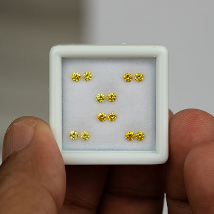 White tray of six yellow diamond pairs held in a hand for size context.