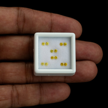 Six yellow diamond pairs in a white tray on an open palm for scale.