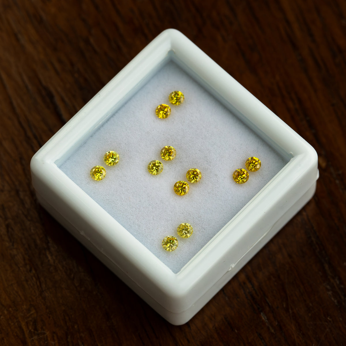 Angled white tray of six yellow diamond pairs on a wood surface.