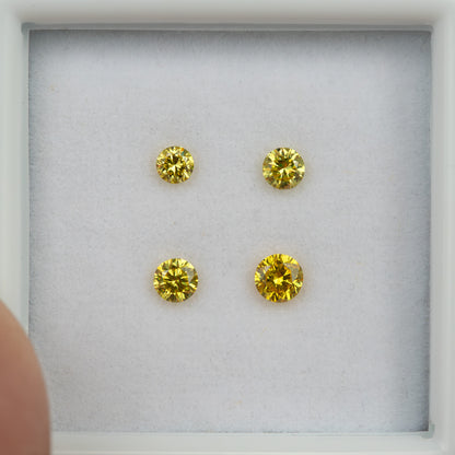 Front view of four yellow round diamonds in two rows inside a white tray.