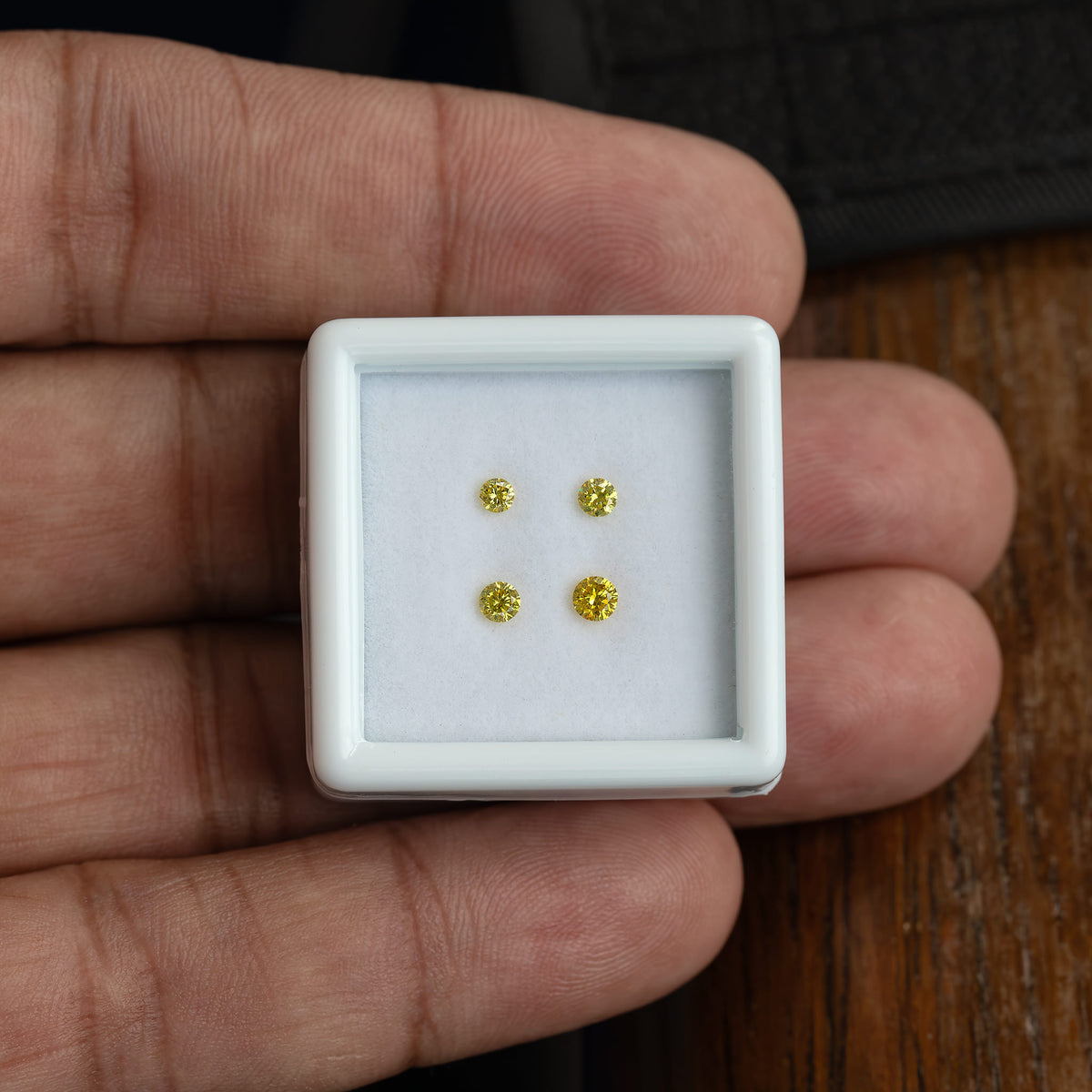 White tray of four yellow diamonds resting on a palm for size reference.