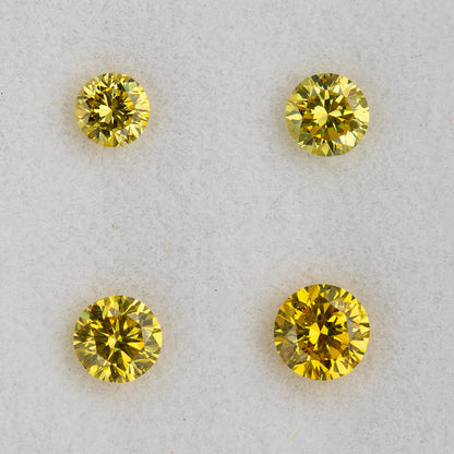 Close face-up comparison of four individual yellow round brilliant diamonds.