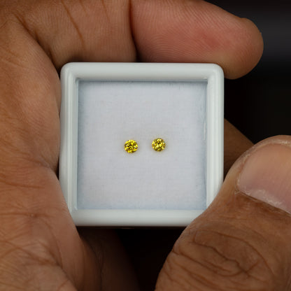 Handheld view of the two matched canary yellow round diamonds