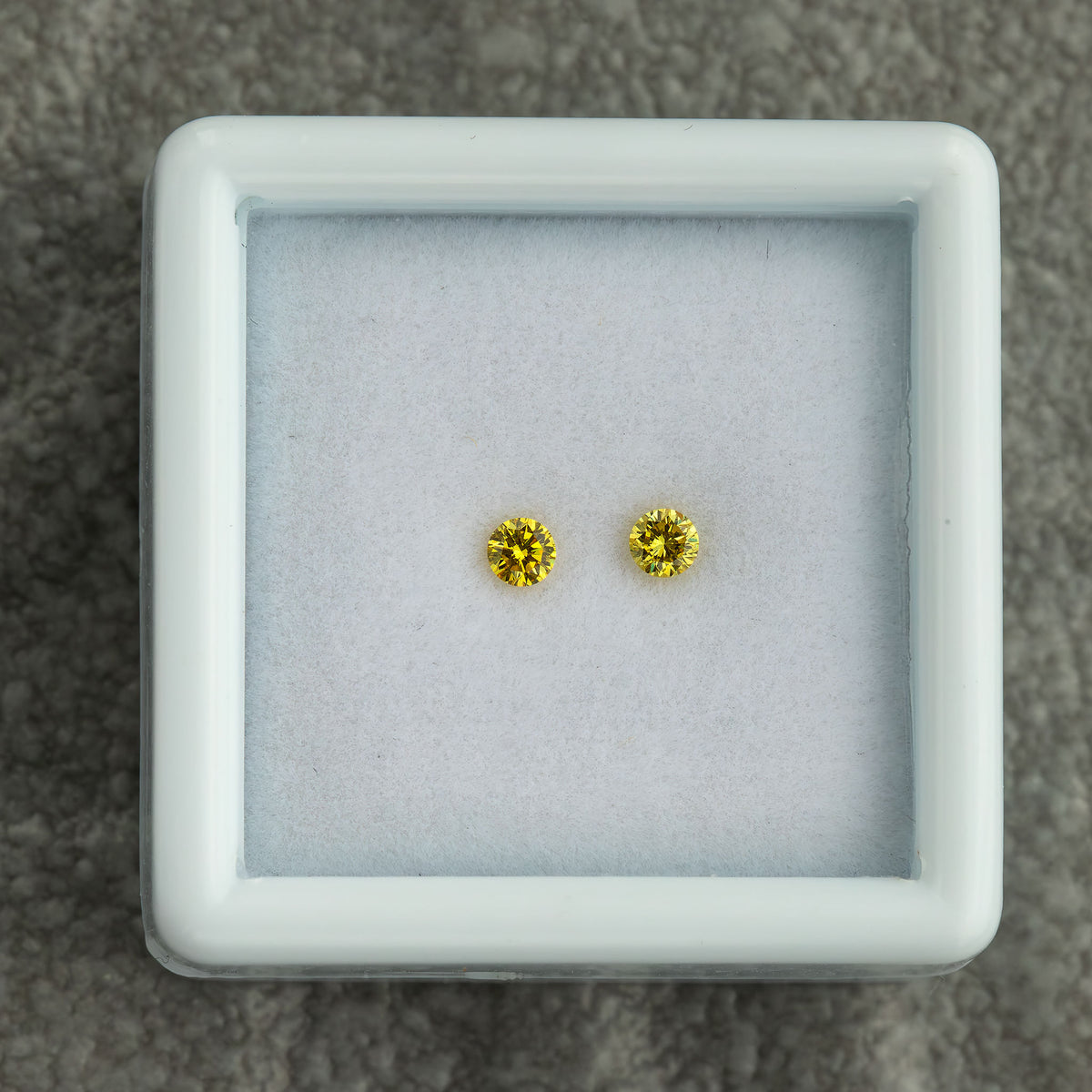 Matched canary yellow round diamond pair displayed together in a box