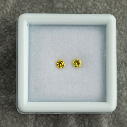 Matched canary yellow round diamond pair displayed together in a box
