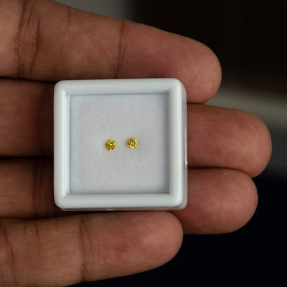 Matched yellow diamond pair shown on a palm for scale