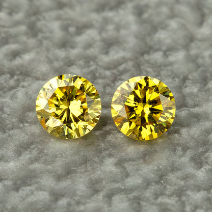 Exact canary yellow diamond pair face-up on a neutral grey surface