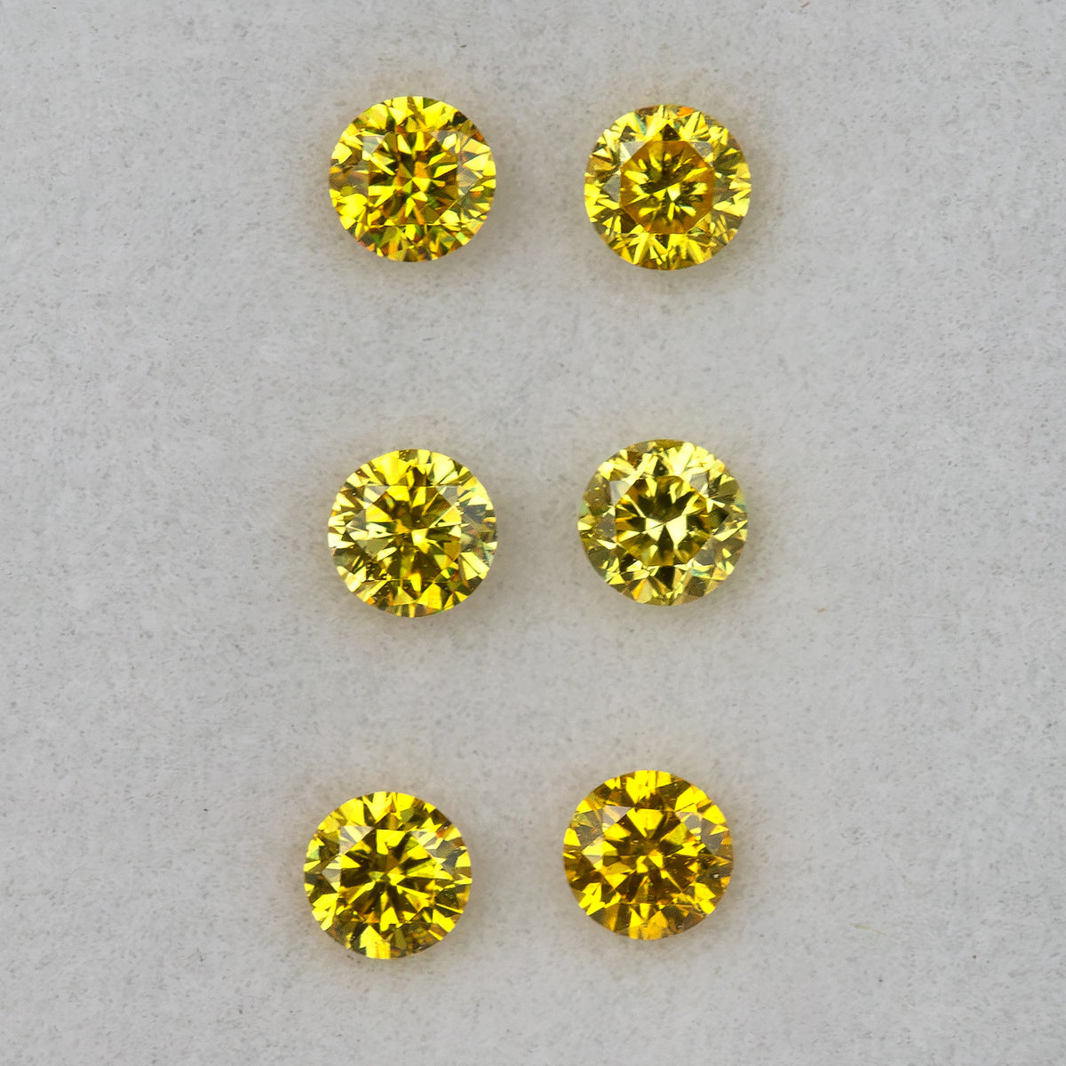 Three yellow diamond pairs arranged in horizontal rows face-up on a pale surface.